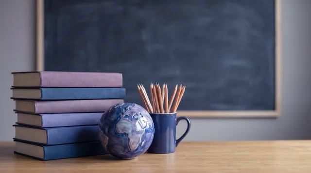 Books, a small globe and a pencil cup on a study desk, illustrating Andrew Hillman's publications