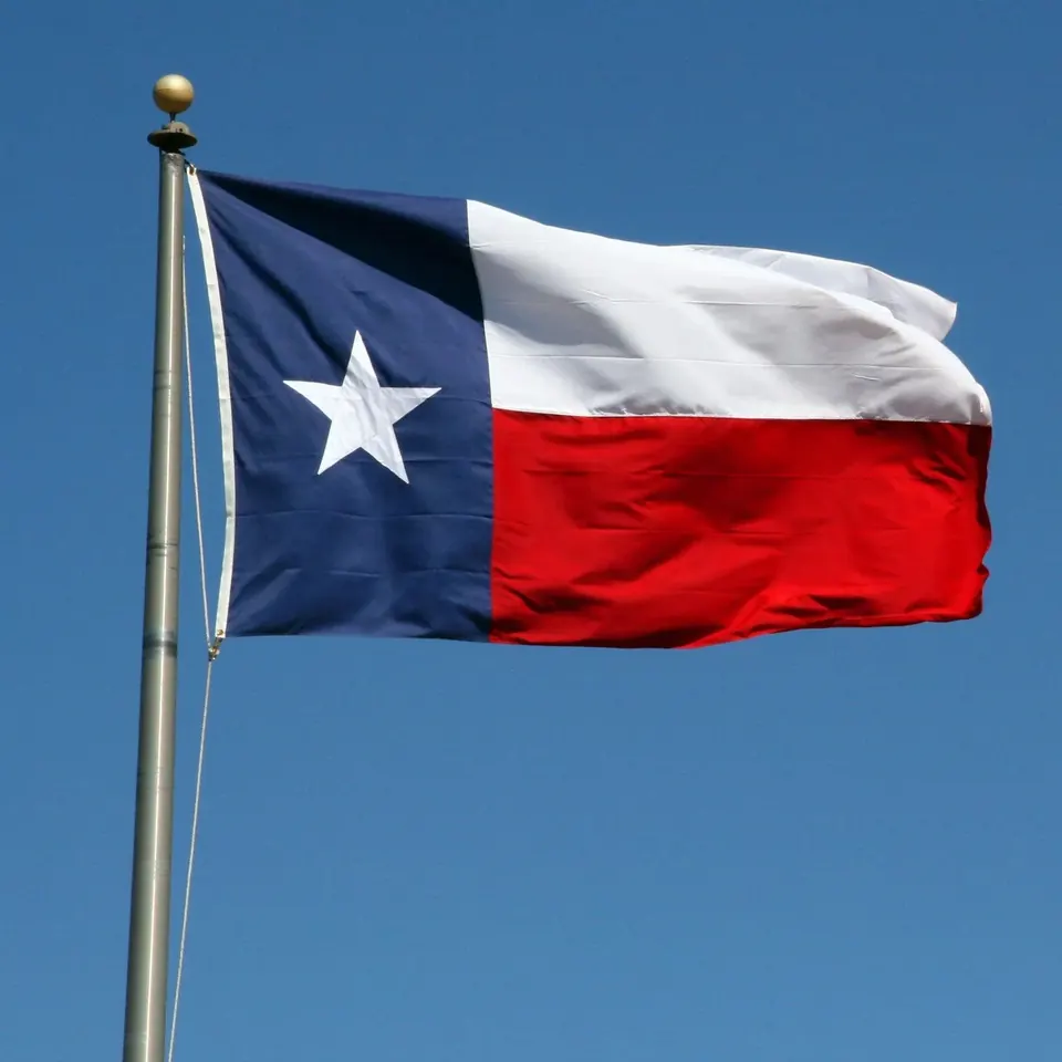 Texas flag flying against a clear blue sky on Andrew Hillman's ventures site